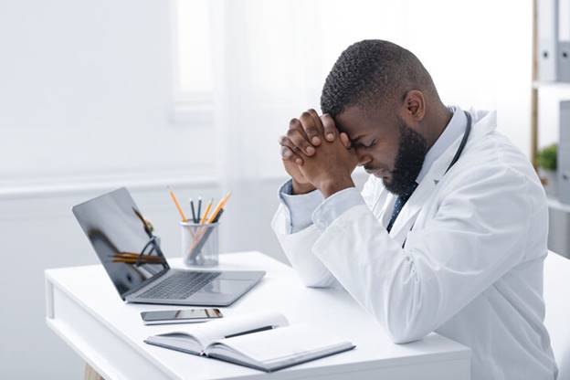 A doctor sitting at a desk with his hands together
AI-generated content may be incorrect.